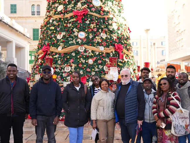 Ascencia Malta students and staff posing in front of a Christmas tree during a festive outing