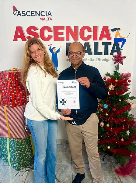 Student receiving certificate at Ascencia Malta with Christmas decorations