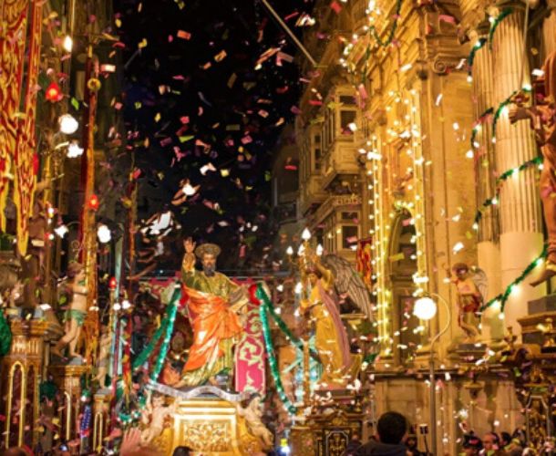 Traditional Malta religious procession with saint statue, colourful street decorations, confetti, and vibrant festa celebration in historic Maltese streets
